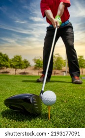 An extreme closeup of the golf driver and ball on the grass with a golfer ready to swing the driver. driver close-up view. selective focus golf driver and out of focus golfer. shot of golf club - Shutterstock ID 2193177091