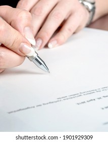 Extreme close-up of the hand of a business woman doing signature and paperwork with a silver pen in her office 
