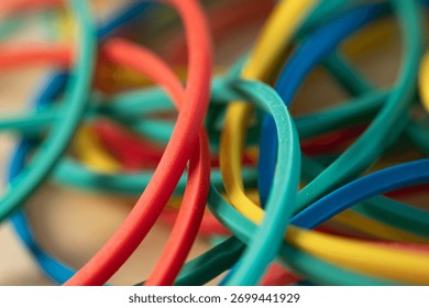 Extreme close-up macro of interlocking, multi-colored rubber bands (red, yellow, blue, green) with a very shallow depth of field, forming an abstract and vivid background.