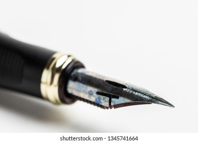 An extreme close-up or macro shot of the stylized and flexible ink-soaked metal nib on a fountain pen set on a white background in horizontal image format.