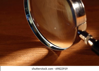 Extreme Closeup Of Magnifying Glass Standing On Wooden Surface With Beam Of Light