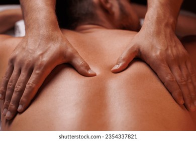 Extreme closeup of masseurs male hands gently pressing hands along clients back. Concept of aesthetic relaxing massage in spa salon, recovery, reboot.
