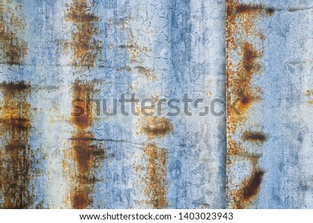 Extreme closeup rust marks texture by heavy weather on long-running white painted galvanized steel corrugated sheets fence. Smooth light in morning made to show sharp texture of rust on zinc.