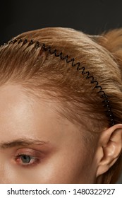 Extreme Close-up Shot Of A Young Blonde European Girl With A Black Hairband In The Form Of A Spiral Spring In Her Hair. The Fashion Model With Nude Make-up Is Looking Away. 