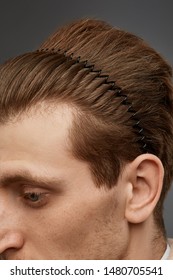 Extreme Close-up Shot Of A Young Chestnut European Man With A Black Hairband In The Form Of A Spiral Spring In His Hair. The Fashion Model With An Unshaved Cheek-bone Is Looking Away. 