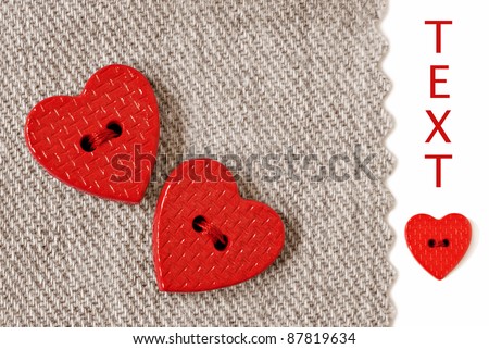 Extreme closeup of tiny heart shaped buttons sewn on natural cotton fabric with white background and copy space.
