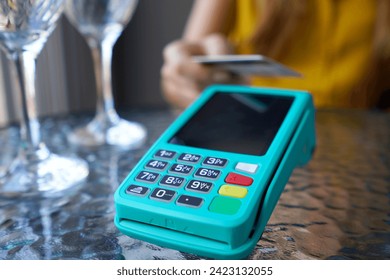Extreme close-up of unrecognizable customer using credit card for online payment. NFC contactless payment by credit card and pos terminal at the cafe.