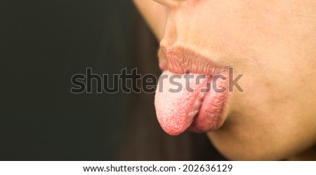 Extreme close-up of a young woman sticking her tongue out