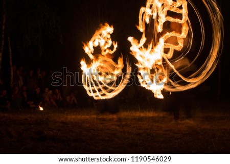 extreme and dangerous the art of taming fire, fireshow colorful shot with long exposure, artists draw intricate shapes glowing postaramy and staffs, a fascinating spectacle on the festival night
