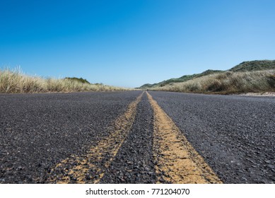 Extreme Low Angle Of Road With Grasses Over Sand Dunes