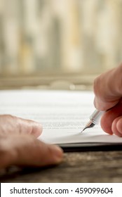 Extreme low angle view on high quality fountain pen in hand writing personal signature on paper.