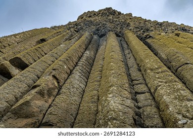 Extreme low-angle view of the towering hexagonal basalt columns at the Giant's Causeway UNESCO World Heritage Site.