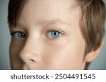 Extreme macro close-up portrait of face. Child boy eyes looking at camera. Blue eyes of teen boy male. Caucasian kid wide opening eyes, smiling. Laser correction
