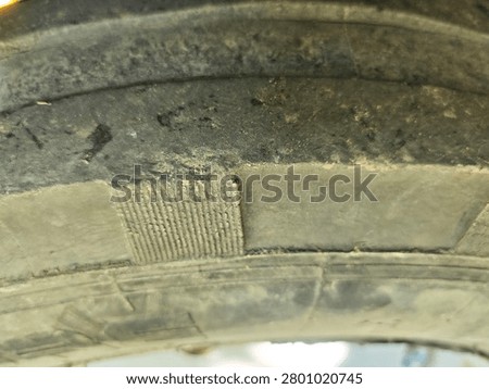 Extreme macro close-up of a worn rubber tire surface with tread patterns and dust texture. Factual detailed view of industrial or agricultural machinery tire material.