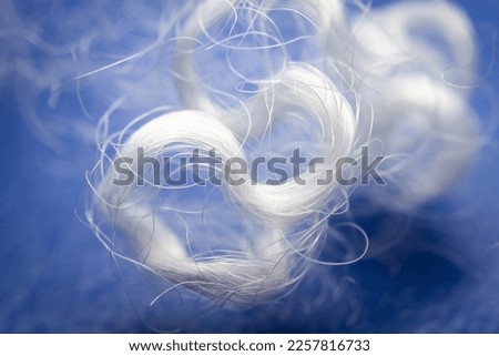 Extreme macro of polyester stable fiber on blue background. Selective focus, shallow depth of field. Abstract dreamy background