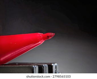 Extreme macro shot of a sharp red marker felt tip pen against a dark gradient background
