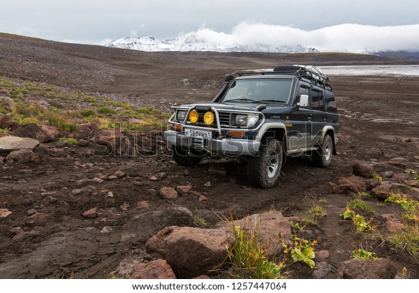 Extreme off-road expedition auto Toyota Land Cruiser\
Prado 70 series driving on mountain road on background of volcanic\
landscape in cloudy autumn weather. Kamchatka Peninsula, Russia -\
Sep 17, 2016