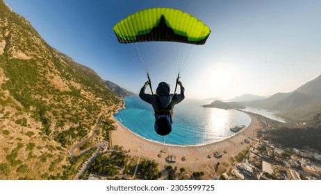 Extreme paraglider pilot flying over the beach, adventure concept.