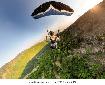 Extreme paraglider pilot flying over Bulgarian mountains, adventure concept. - Shutterstock ID 2346323913