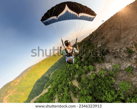 Extreme paraglider pilot flying over Bulgarian mountains, adventure concept.
