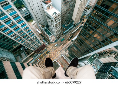 Extreme Photography Concept, Man Sitting At The Edge Of A Building Taking Photo