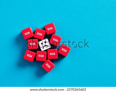 Extreme risk taking, stress and frustration. Too many risk factors. Risky business environment. Unhappy face surrounded with cubes with the word risk.