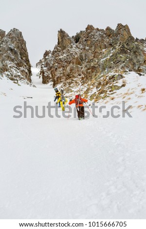 Extreme skiers climb to the top along the couloir between the rocks before the descent of the freeride backcountry