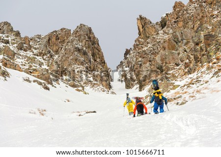 Extreme skiers climb to the top along the couloir between the rocks before the descent of the freeride backcountry