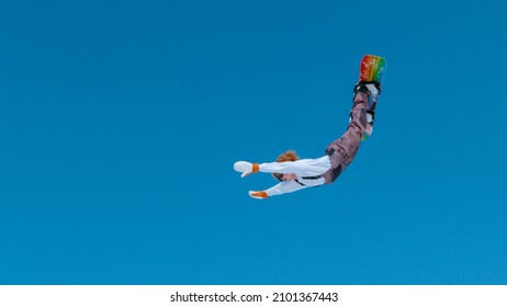 Extreme Snowboarder Catches Big Air And Does A Spectacular Backflip With Outstretched Arms. Action Shot Of A Stoked Male Tourist Doing A Tumbling Trick While Snowboarding In The Scenic Julian Alps