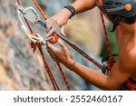 Extreme sport climbing on summer beach holiday vacation. Asian man climber enjoy outdoor active lifestyle preparing hanging rope and safety equipment for climbing on rocky mountain at tropical island.