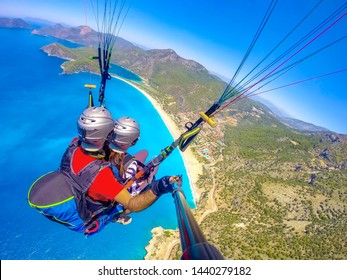 Extreme Sport. Landscape . Paragliding In The Sky. Paraglider Tandem Flying Over The Sea With Blue Water And Mountains In Bright Sunny Day. Aerial View Of Paraglider And Blue Lagoon In Oludeniz, Turke