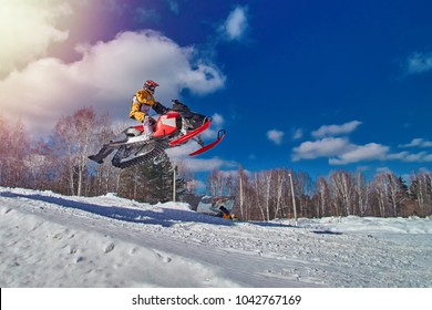 Extreme Sport Race Snowmobiles. Snowmobile In High Jump Above Track. Sportsman On Snowmobile. Winter Competition, Sunny Day. Trick Against Blue Sky. Snow Motor Sports Copy Space.