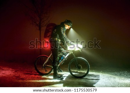 Extreme Sport race.Winter Enduro Biking challenge. Biker check possition in map. Lost way under fresh snow. Winter misty night  with snow. 