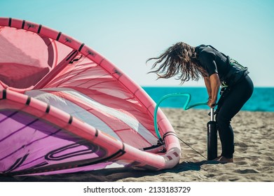 Extreme sport woman preparing equipment for kitesurfing and inflates it with air pump for kite surfing. - Powered by Shutterstock