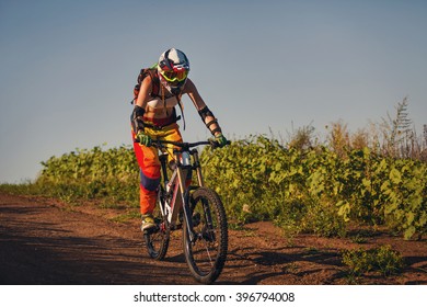 Extreme summer sports - young sportive strong woman or sportswoman riding downhill on mountain bicycle in helmet and other protective gear - Shutterstock ID 396794008