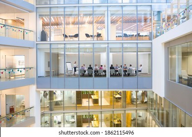 An Extreme Wide View Of Businesswomen And Businessmen Having An Important Meeting In A Conference Room Seen Through The Glass Walls From Outside Of A Modern Building