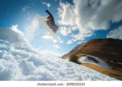 Extreme winter sports. Young professional woman snowboarder rides a halfpipe. Jumps from a halfpipe trampoline in the sun, performs tricks and turns with grabs in a sunny winter