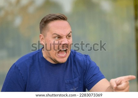 Extremely angry aggressive young man yelling and pointing at someone