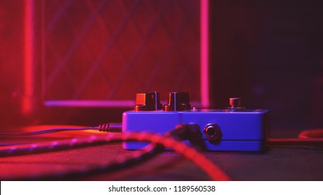 Extremely close up of button for effect electro guitar pedal. Red neon light in night club during show concert - Powered by Shutterstock