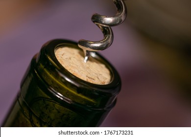 Extremely close up view of bottleneck of wine bottle and bottle-screw swirling cork. Wine bottle opening