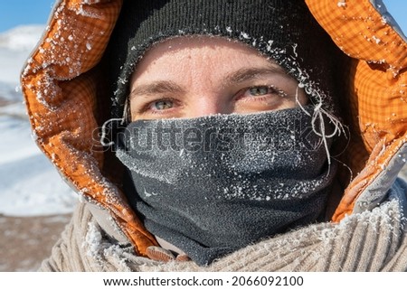 Extremely cold weather. Portrait of young woman with face covered with snow frost.