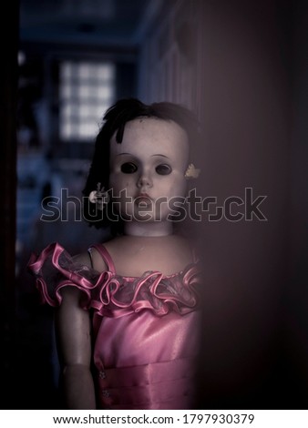 Extremely creepy doll with blank expression at the back of the door. Horror or disturbing concept.