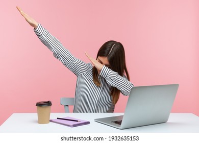 Extremely Excited Happy Woman Office Worker Showing Dab Dance Gesture, Performing Internet Meme Of Success, Sitting At Workplace With Laptop. Indoor Studio Shot Isolated On Pink Background