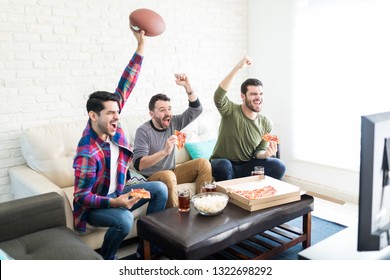 Extremely Happy Friends With American Football Watching TV In Living Room