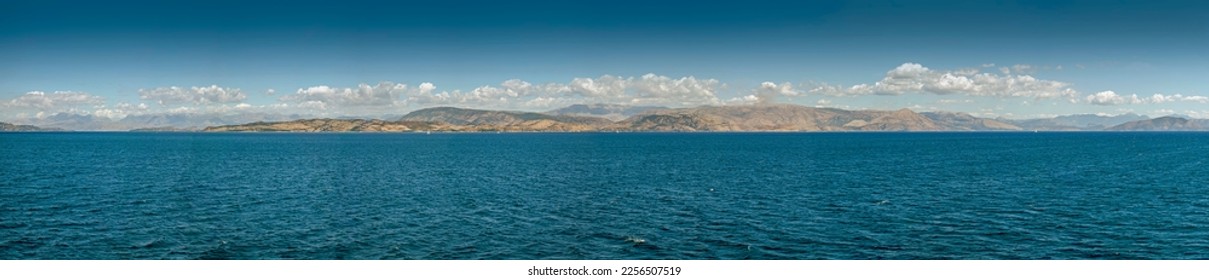 Extremely large panorama of azure sea with white sails, mountains on horizon under blue sky with clouds in Greece on sunny day - Powered by Shutterstock