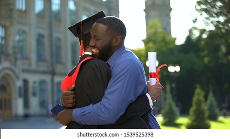 Extremely Proud Afro-american Dad Embracing Graduation Son With Diploma, Joy