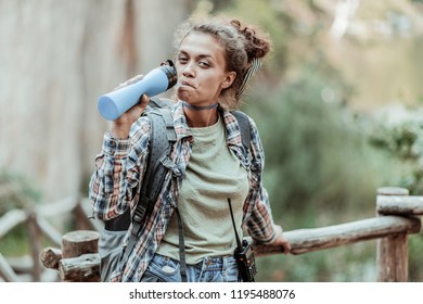 Extremely Thirsty. Dark-haired Female Backpacker Feeling Extremely Thirsty After Hiking Really High With Her Friend