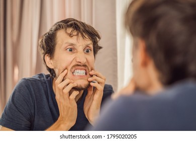 Extremly Tired Young Man Looking At Himself In The Mirror, Home Alone. Self-isolation At Home, Quarantine Due To Pandemic COVID 19. Mental Health Problems In Self-isolation At Home