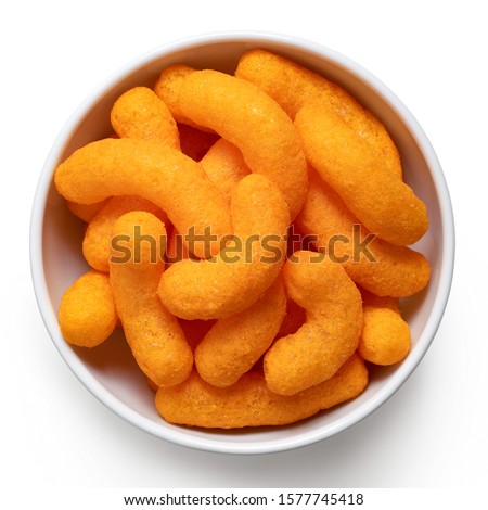 Extruded cheese puffs in a white ceramic bowl isolated on white. Top view.