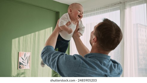 Exuberant Baby Laughing While Being Lifted High by Father Indoors - Powered by Shutterstock